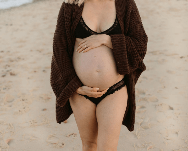 Best Third Trimester Checklists pregnant woman on beach holding her pregnant belly 